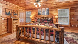 A log cabin bedroom with a wooden bed, a ceiling fan, and a window with blinds. - Making Memories You'll Never Forget (SEVIERVILLE)