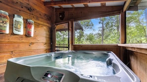 Une cabane en bois dotée d’un bain à remous, de murs en bois et de pots de miel disposés sur le mur.