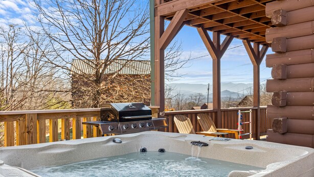 Un bain à remous sur une terrasse en bois, avec vue sur les montagnes.