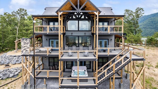 Une cabane en bois à plusieurs étages, dotée d’un jacuzzi au rez-de-chaussée, entourée d’une terrasse et d’un espace salon extérieur.