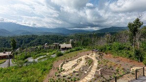 A scenic view of a mountainous area with a winding stone pathway, houses, and lush greenery.
