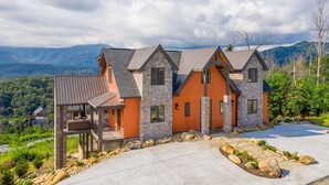 A large, multi-story house with a stone facade, multiple chimneys, and a balcony.