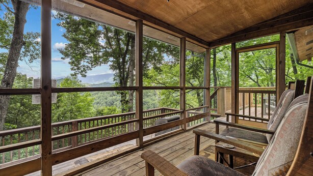 A wooden deck with large windows offering a view of a forested area. - Mountain Views-Hot Tub-Fireplace-Close to Dollywood (SEVIERVILLE)