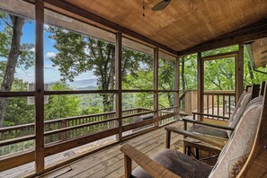 A wooden deck with large windows offering a view of a forested area. - Mountain Views-Hot Tub-Fireplace-Close to Dollywood (SEVIERVILLE)
