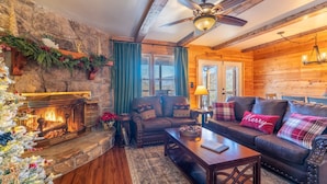 A cozy log cabin interior with a fireplace, wooden furniture, and a Christmas tree. - Mountain Views-Hot Tub-Fireplace-Close to Dollywood (SEVIERVILLE)