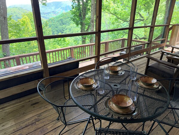 A round metal table with four bowls and glasses, set on a wooden deck with a view of a forested landscape through large windows. - Mountain Views-Hot Tub-Fireplace-Close to Dollywood (SEVIERVILLE)