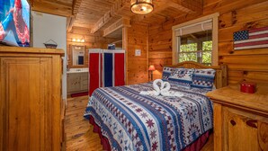 A wooden cabin room with a bed, a dresser, a vanity, and a television. - Freedom Rings Where Mountains Sing (SEVIERVILLE)