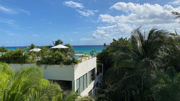A modern building with a pool and a view of the ocean. - Beach, Pool, Hot Tub, Billiard Room, Arcade equals awesome vacation! (Playa del Carmen)
