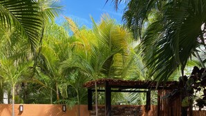 A swimming pool with a stone structure and grill, surrounded by palm trees and a wooden fence. - Beach, Pool, Hot Tub, Billiard Room, Arcade equals awesome vacation! (Playa del Carmen)