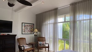 A bedroom with a large bed, two wooden chairs, a small table, a TV, and a painting on the wall. - Beach, Pool, Hot Tub, Billiard Room, Arcade equals awesome vacation! (Playa del Carmen)