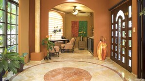 A spacious hallway with a marble floor, a dining area with chairs and a table, and a large wooden door with glass panels. - Beach, Pool, Hot Tub, Billiard Room, Arcade equals awesome vacation! (Playa del Carmen)