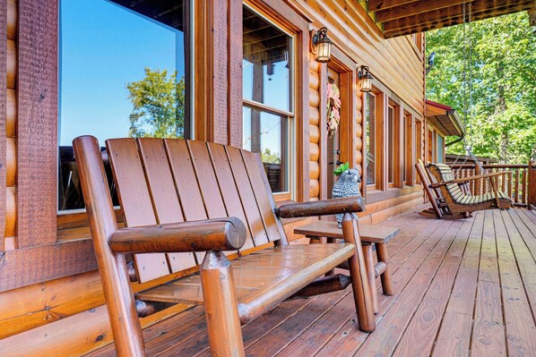 A wooden deck with outdoor seating and a view of the surrounding nature.