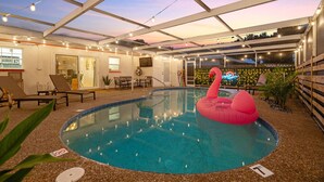 An indoor pool area with a glass ceiling, lounge chairs, and a pink flamingo inflatable. - Boho Heated Pool House w/Gym <20min to Beaches! (Largo)