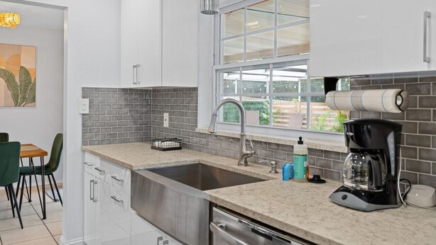 A modern kitchen with a large sink, a coffee maker, and a window with a view of the outdoors. - Boho Heated Pool House w/Gym <20min to Beaches! (Largo)
