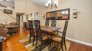 A dining area with a wooden table and chairs, a chandelier, and a large mirror on the wall. - A Luxury Plus Level Hideout (PIGEON FORGE)