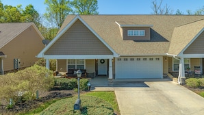 A two-story house with a garage, a covered porch, and a front yard with landscaping. - A Luxury Plus Level Hideout (PIGEON FORGE)