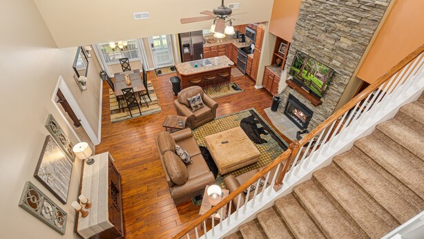 A spacious living area with a fireplace, wooden flooring, and a high ceiling with a fan. - A Luxury Plus Level Hideout (PIGEON FORGE)