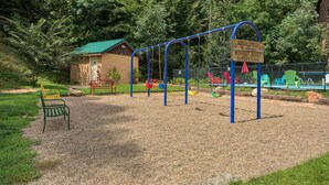Un parque infantil con columpios y un letrero que indica 'ABSOLUTELY NO CHILDREN WITHOUT ADULT SUPERVISION'.