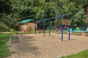 Un parque infantil con columpios y un letrero que indica 'ABSOLUTELY NO CHILDREN WITHOUT ADULT SUPERVISION'.