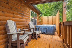 A wooden deck with Adirondack chairs and a hot tub.
