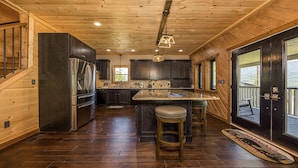 A modern kitchen with dark wood cabinets, stainless steel appliances, and a large island with stools. - If Every View Could Be This Perfect (GATLINBURG)