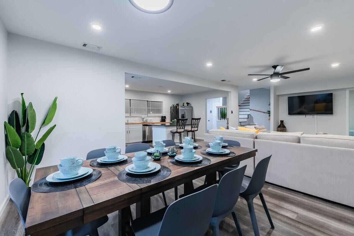 A modern dining area with a wooden table set for six, surrounded by chairs.