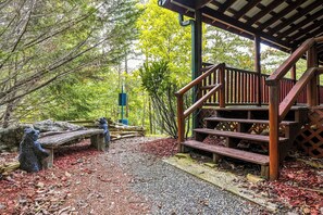 A wooden staircase leading to a covered area with a bench and a stone bear statue.