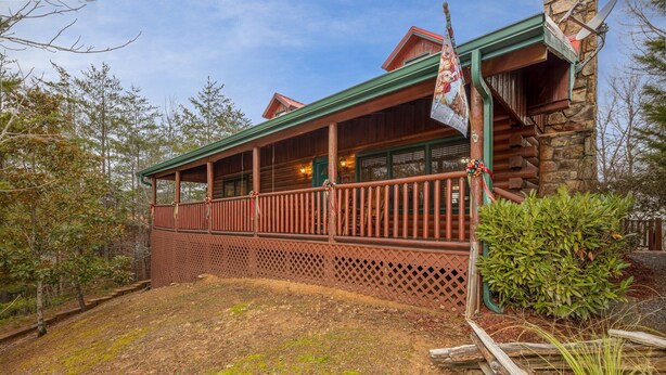A rustic cabin with a wooden porch, stone walls, and a flag.