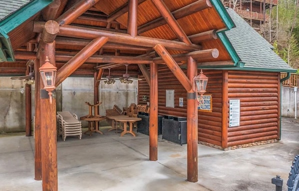 A log cabin with a covered patio area, wooden furniture, and a sign indicating diving is allowed.