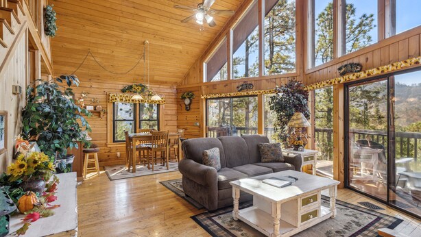 A spacious wooden interior with a large sofa, dining table, and chairs. - Get Away From The Grind For Some Tlc (PIGEON FORGE)