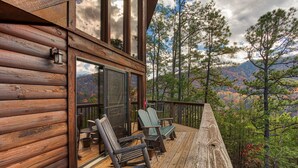 A wooden deck with rocking chairs and a glass door leading to a deck area. - Get Away From The Grind For Some Tlc (PIGEON FORGE)