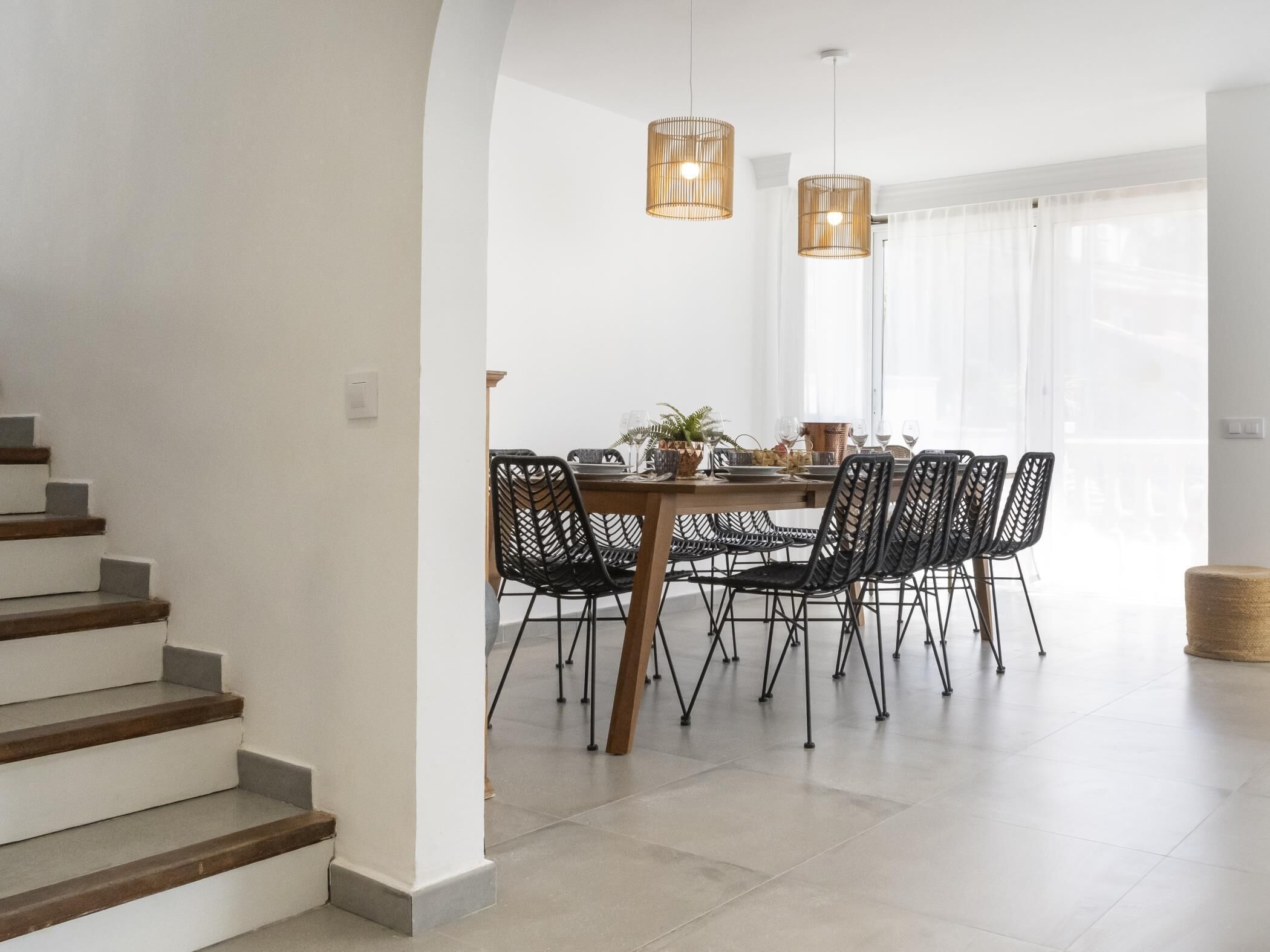 Een eethoek met een ronde tafel, zwarte stoelen en twee hanglampen.