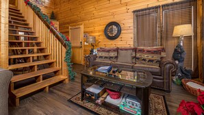 Ein Holzinnenraum mit Treppe, einer Sofagarnitur, einem Couchtisch und einem Weihnachtsbaum.