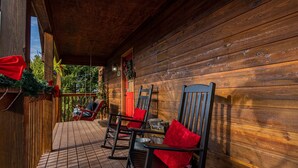 Eine Holzhütte mit Veranda, Schaukelstühlen und einem Weihnachtsgesteck.