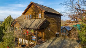 Ein zweistöckiges Holzhaus mit Veranda, einer kleinen angebauten Garage und einem eingezäunten Garten.
