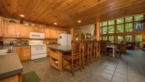 A wooden cabin kitchen with a central island, wooden cabinets, a stove, and a refrigerator. - Accessible (Not ADA)*Gatlinburg*Relaxing (SEVIERVILLE)