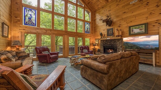 A spacious living room with a fireplace, large windows, and a mounted deer head. - Accessible (Not ADA)*Gatlinburg*Relaxing (SEVIERVILLE)