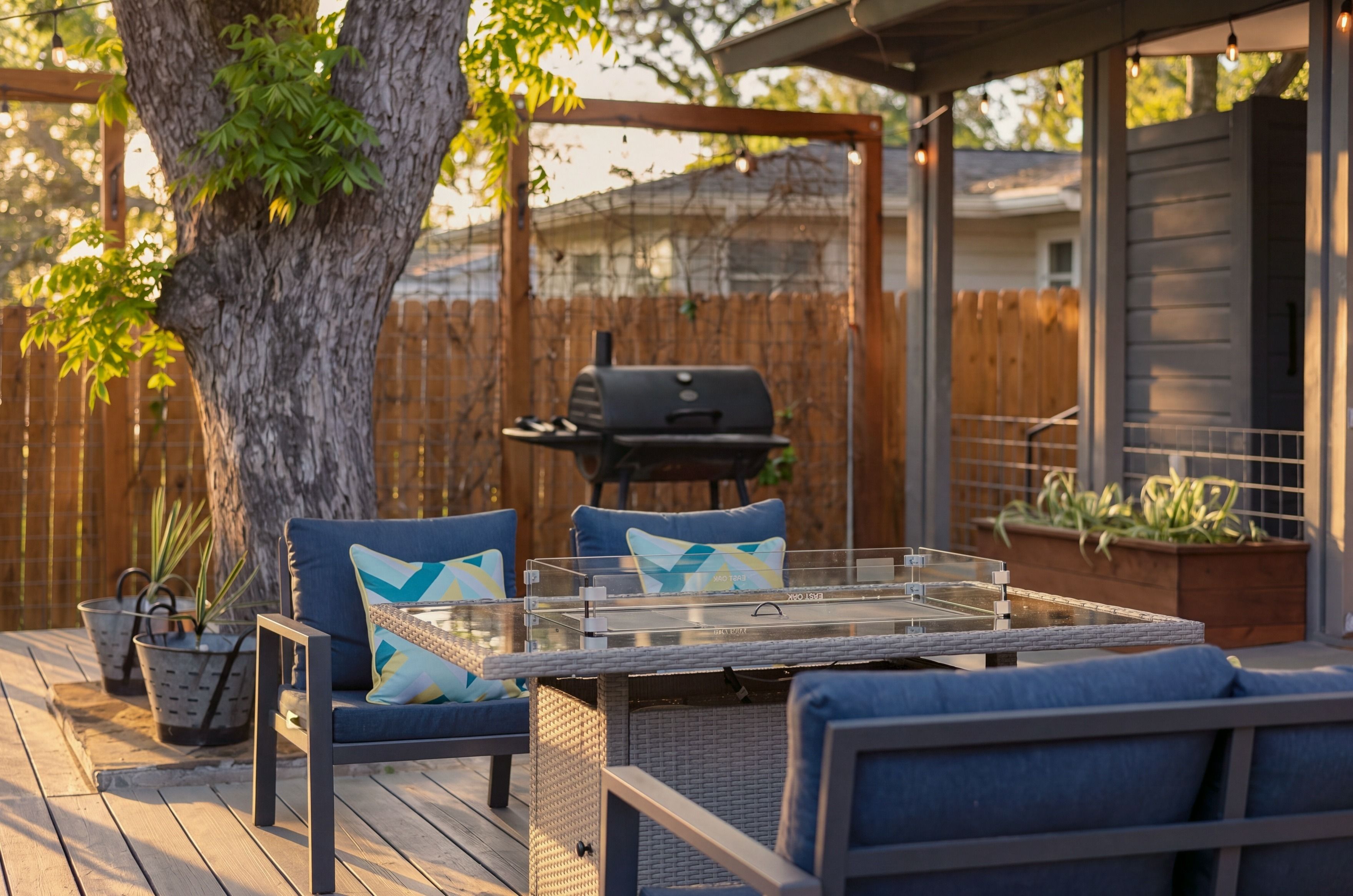 An outdoor patio with a table and chairs, a grill, and a wooden deck.