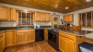 A kitchen with wooden cabinets, a dishwasher, an oven, and a granite countertop. - Firepit - Mountain Views - Car Show Friendly (GATLINBURG)