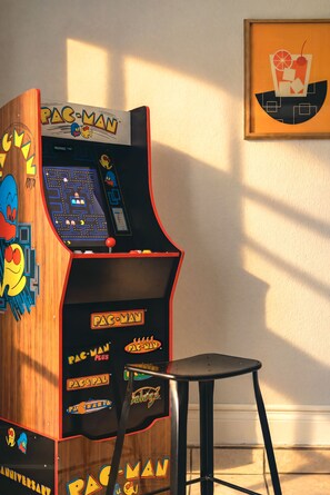 A vintage Pac-Man arcade machine with a wooden finish and a small stool in front. - Private Hot Tub & Game Room near SeaWorld and Lackland AFB (San Antonio)