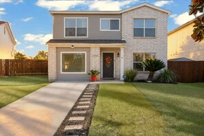 A two-story house with a front entrance, a garage, and a well-maintained lawn. - Private Hot Tub & Game Room near SeaWorld and Lackland AFB (San Antonio)