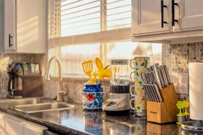A kitchen with a sink, a blender, a coffee maker, and utensils on the counter. - Private Hot Tub & Game Room near SeaWorld and Lackland AFB (San Antonio)