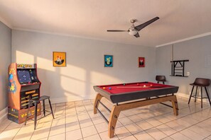 A room with a pool table, a ceiling fan, and a Pac-Man arcade game. - Private Hot Tub & Game Room near SeaWorld and Lackland AFB (San Antonio)