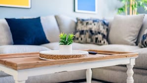 A living room with a white table, a small potted plant, and a remote control on the table. - Private Hot Tub & Game Room near SeaWorld and Lackland AFB (San Antonio)