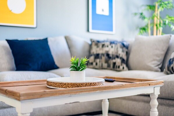 A living room with a white table, a small potted plant, and a remote control on the table.