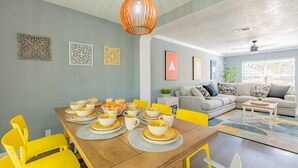 A dining area with a wooden table set for four, yellow chairs, and a hanging light fixture. - Private Hot Tub & Game Room near SeaWorld and Lackland AFB (San Antonio)