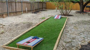 A backyard with a shuffleboard table and a small tree.