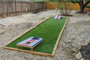 Un jardin avec une table de jeu de palet et un petit arbre.