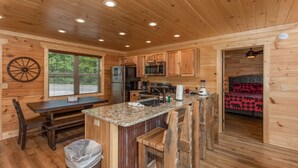 A wooden cabin interior with a kitchen, dining area, and a bedroom. - Private Pool*Home Theater w/ 4K TV (SEVIERVILLE)