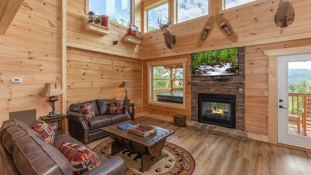 A cozy log cabin interior with a fireplace, leather furniture, and wooden walls. - Private Pool*Home Theater w/ 4K TV (SEVIERVILLE)